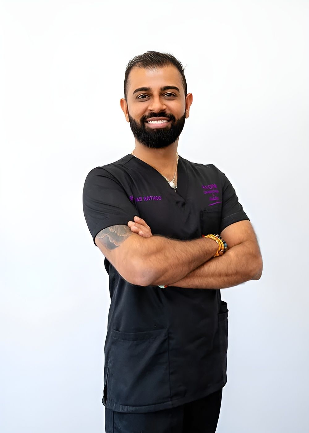 Smiling professional in medical scrubs with crossed arms.