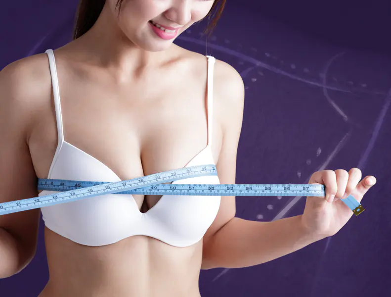 Woman with curly hair smiling against white wall.