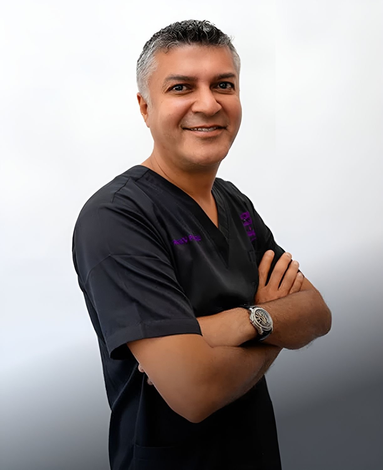 Smiling professional in medical scrubs with crossed arms.